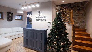 Et receptionområde med et juletræ, et blåt receptionsskrivebord, en trappe og en stenvæg.
