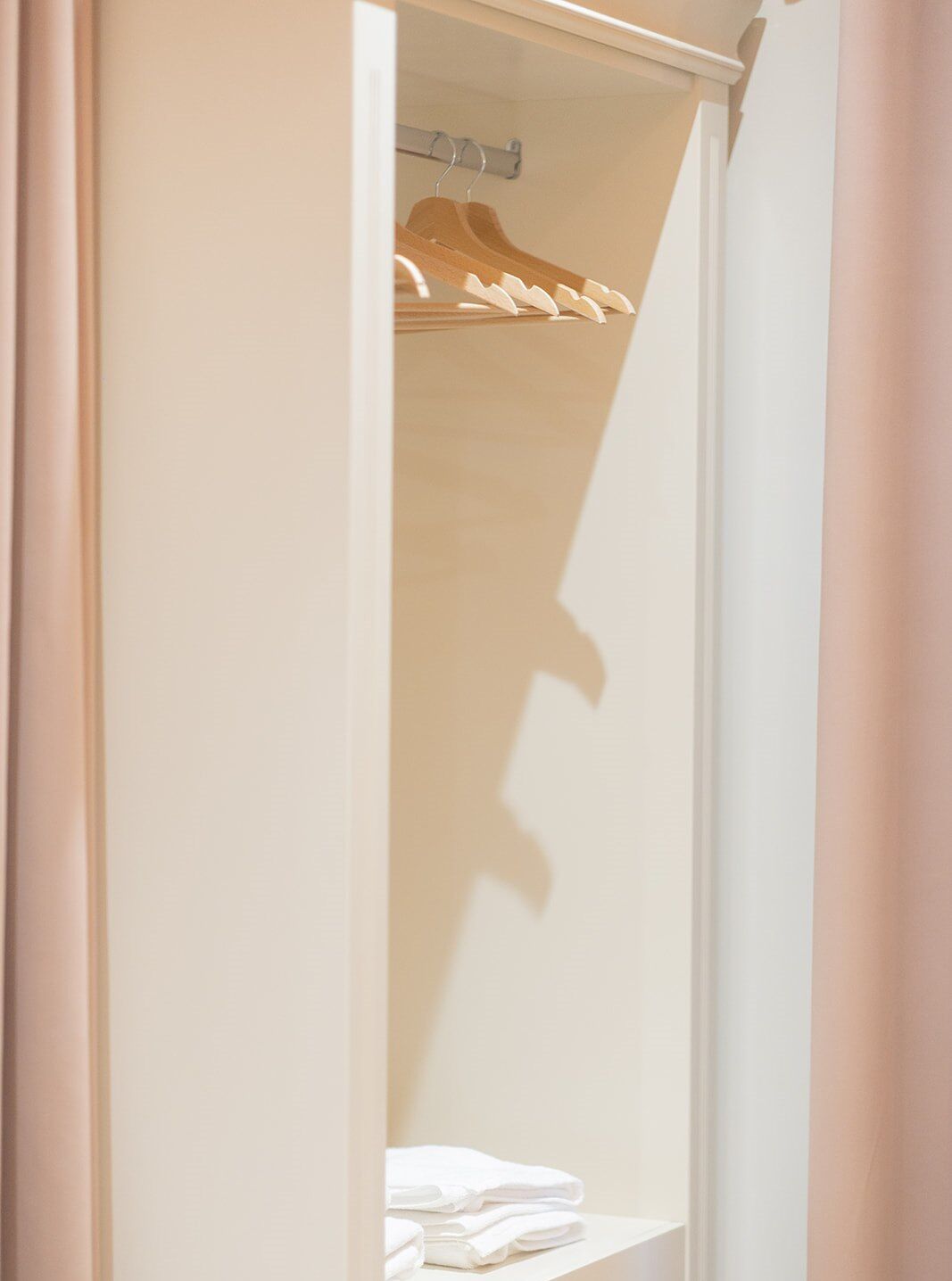 A closet with wooden hangers and folded white towels.