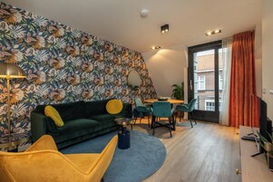 Ein modernes Wohnzimmer mit einem grünen Sofa, einem gelben Sessel und einem runden Couchtisch.