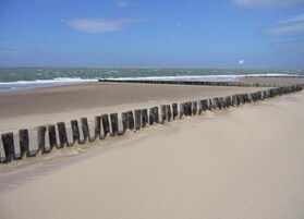 A beach with a wooden groyne separating the sand from the sea.