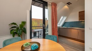 Une cuisine moderne avec une fenêtre, un coin repas comprenant une table et des chaises, et une plante en pot.