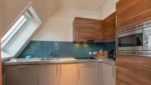 A kitchen with a skylight, wooden cabinets, a stainless steel microwave, and a blue-tiled backsplash. - Apartment in Zoutelande Near the Beach (Zoutelande)