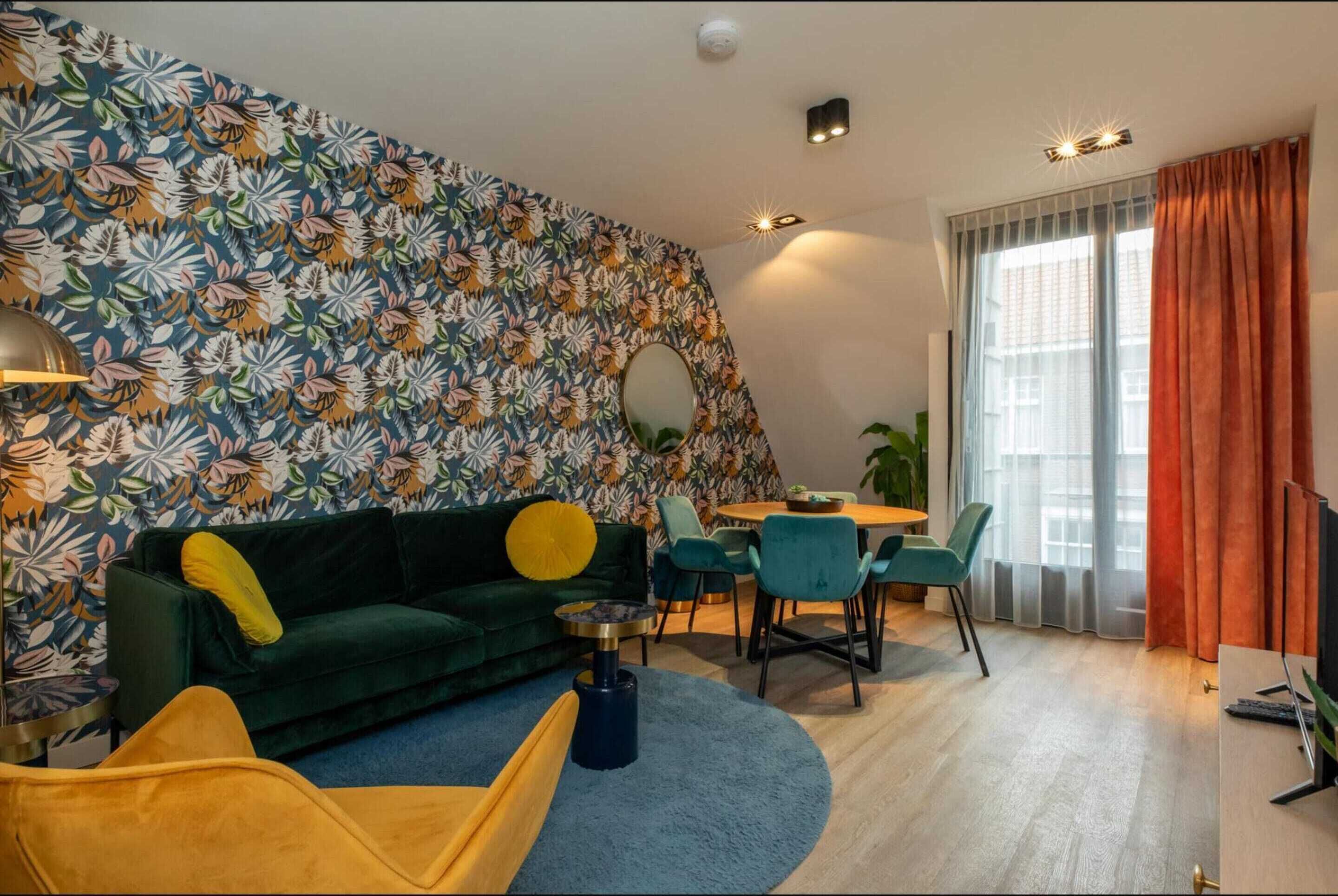 Una sala de estar moderna con un sofá verde, un sillón amarillo y una zona de comedor con una mesa redonda y sillas.