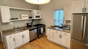 A modern kitchen with white cabinetry, stainless steel appliances, a built-in oven, microwave, and a refrigerator.