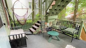 A covered outdoor area with a hammock, a bench, a table, and a staircase.