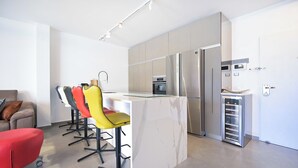 A modern kitchen with a marble island, stainless steel appliances, and a built-in wine cooler. - 3BR Beach&City Vibes in Bugrashov by HolyGuest (Tel Aviv-Yafo)