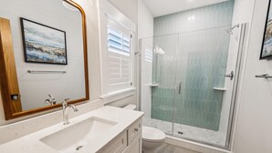 A modern bathroom with a double sink, a toilet, and a glass-enclosed shower. - Daniels -- Brand New Luxury Oceanfront Home (Corolla)