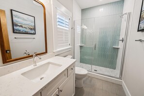 A modern bathroom with a double sink, a toilet, and a glass-enclosed shower.