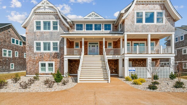 A two-story house with a front porch, multiple windows, and a driveway. - Daniels -- Brand New Luxury Oceanfront Home (Corolla)