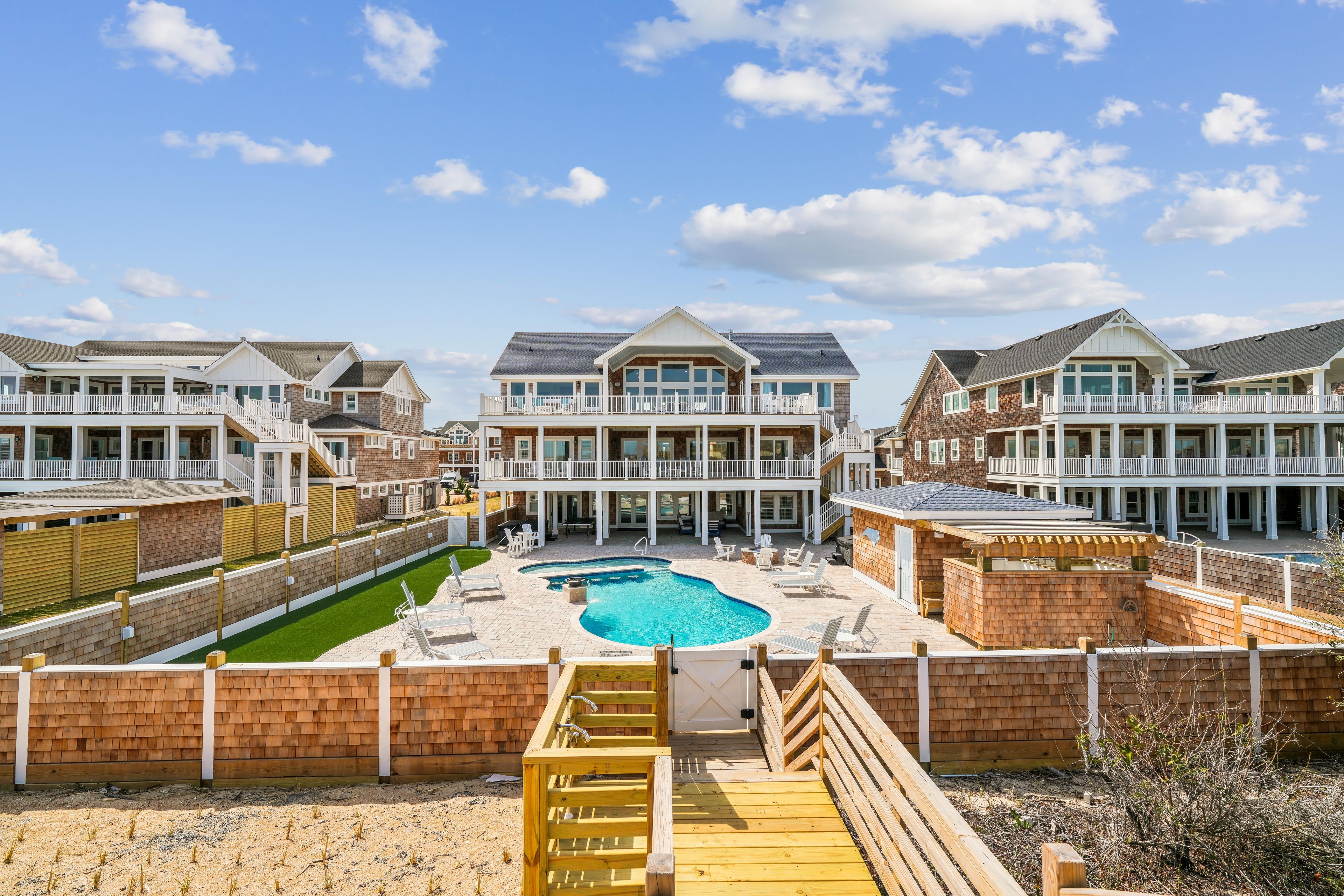 A residential complex with multiple two-story houses, a central swimming pool, and a wooden deck.