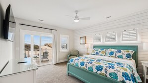 A bedroom with a bed, a desk, a chair, a TV, and a view of the outdoors. - Daniels -- Brand New Luxury Oceanfront Home (Corolla)
