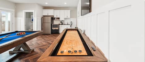 A pool table with a shuffleboard in a modern kitchen area.