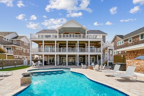 A two-story house with a swimming pool and outdoor seating.