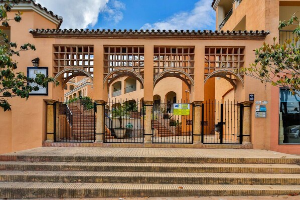 A building with a gated entrance, multiple arches, and a staircase leading up to the entrance.