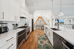Une cuisine moderne avec des meubles blancs, des appareils en acier inoxydable et un plancher en bois.