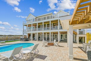 Une maison à deux étages avec une piscine, un espace salon extérieur et un patio couvert.