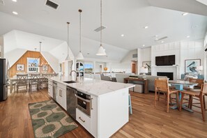 Une cuisine spacieuse dotée d’un grand îlot central, de planchers en bois et d’appareils électroménagers modernes.