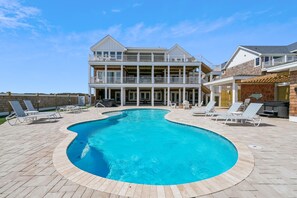 Ein zweistöckiges Haus mit Swimmingpool, Gartenmöbeln und einer Grillgelegenheit.
