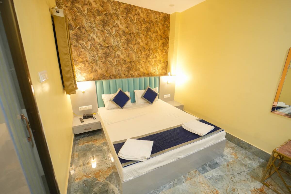 A hotel room with a bed, a headboard, bedside tables, and a mirror.