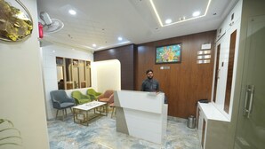 A reception area with a marble floor, wooden paneling, a reception desk, and seating with a green and blue chair. - Kashi Pilgrim Stay (Varanasi)