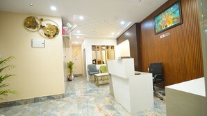 A reception area with a marble floor, wooden paneling, a reception desk, and a framed artwork on the wall. - Kashi Pilgrim Stay (Varanasi)