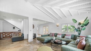 Un amplio salón con un sofá modular grande, una mesa de centro redonda y una escalera que lleva a otro nivel.