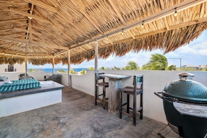 An outdoor patio with a thatched roof, a barbecue grill, and a seating area with a view of the ocean. - Bliss Bonaire by Boutique Bonaire Unique Resorts (Kralendijk)