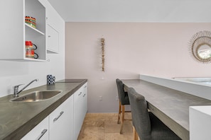 A modern kitchen with a built-in sink, a dining area with a bench, and a decorative wall piece.