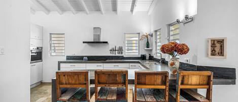 Una cocina moderna con armarios blancos, una isla central y un ventilador de techo.