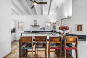 A modern kitchen with white cabinetry, a central island, and a ceiling fan. - Bliss Bonaire by Boutique Bonaire Unique Resorts (Kralendijk)