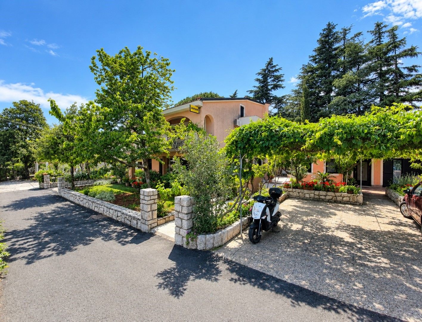 A residential building with a paved driveway and a parked scooter.