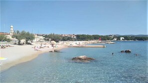 A beach with clear water, a sandy shore, and a few people swimming. - Apartment Cherry – Prime Location, Spacious Terrace, Ideal for Families, Close to the Beach and Center (Krk)
