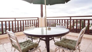 A round table with four chairs, each with a cushioned seat, on a balcony with a view of buildings. - G402 Park View (Peyia Paphos)