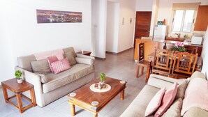 A living room with a sofa, coffee table, and dining table. - G402 Park View (Peyia Paphos)
