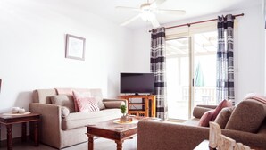 A living room with a sofa, coffee table, and a TV on a wooden stand. - G402 Park View (Peyia Paphos)