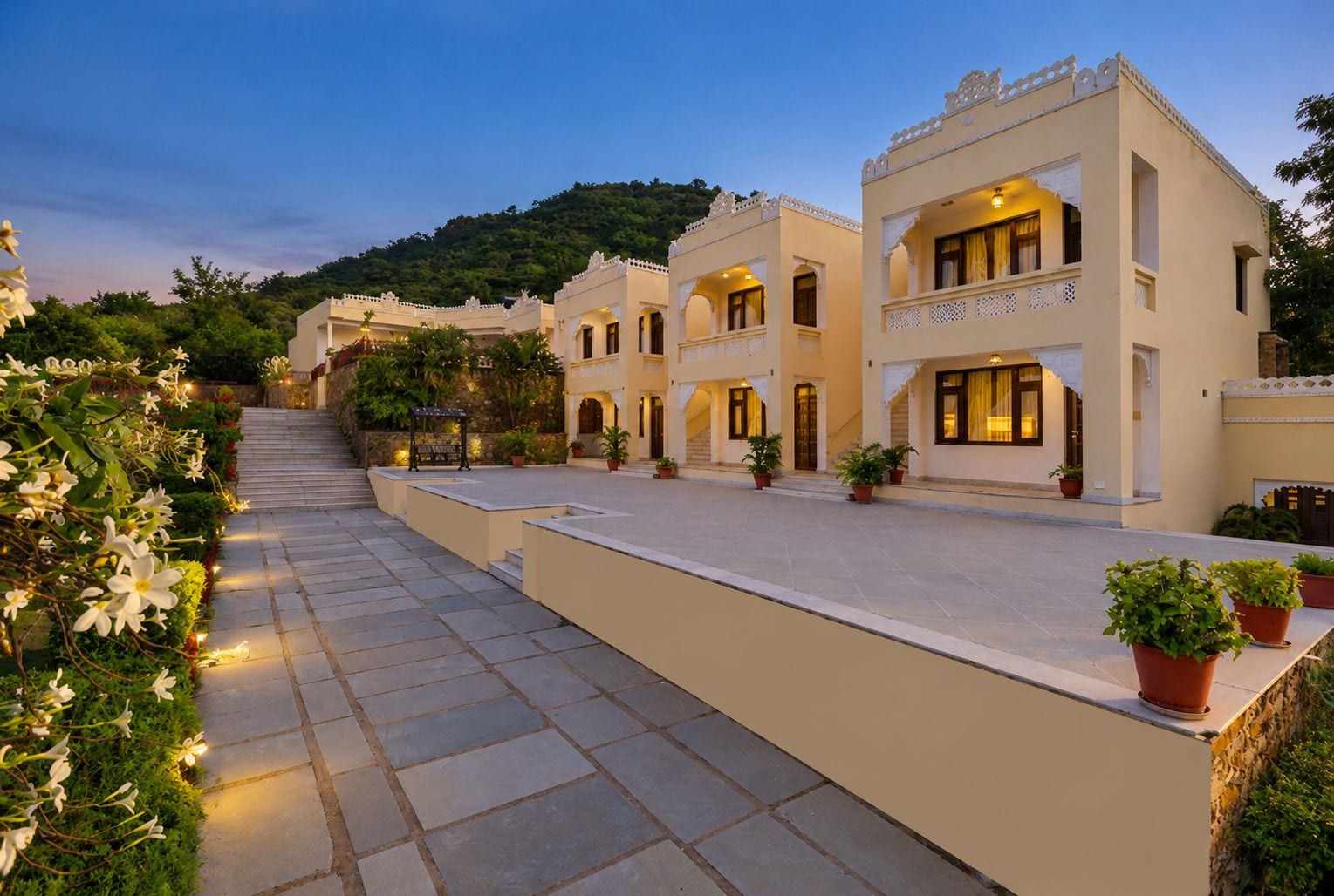 A hotel with a courtyard, multiple buildings, and a staircase leading to a hilltop.
