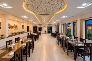 A spacious dining area with long tables, chairs, and a decorative ceiling. - Hill Garden Resort – Near Fateh Sagar, Udaipur (Udaipur)