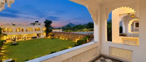 Un balcón de hotel con suelo a cuadros, vistas a un patio bien iluminado y elementos arquitectónicos tradicionales.