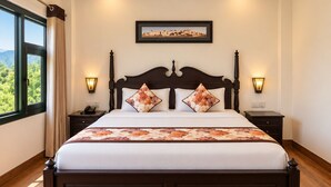 Habitación de hotel con una cama grande, dos mesitas de noche con lámparas, un cuadro enmarcado en la pared y una ventana con cortinas.