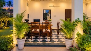 Un comedor interior con suelo a cuadros, muebles de madera y plantas en macetas.