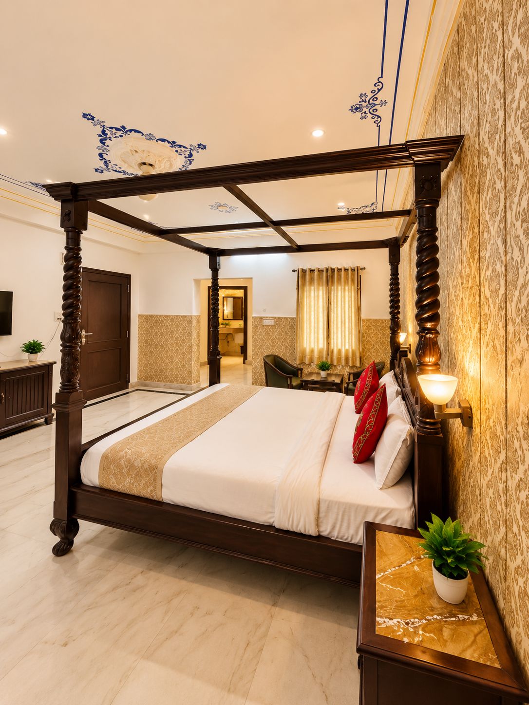 A four-poster bed with a canopy, a bedside table with a lamp, and a view of the bathroom in the background.