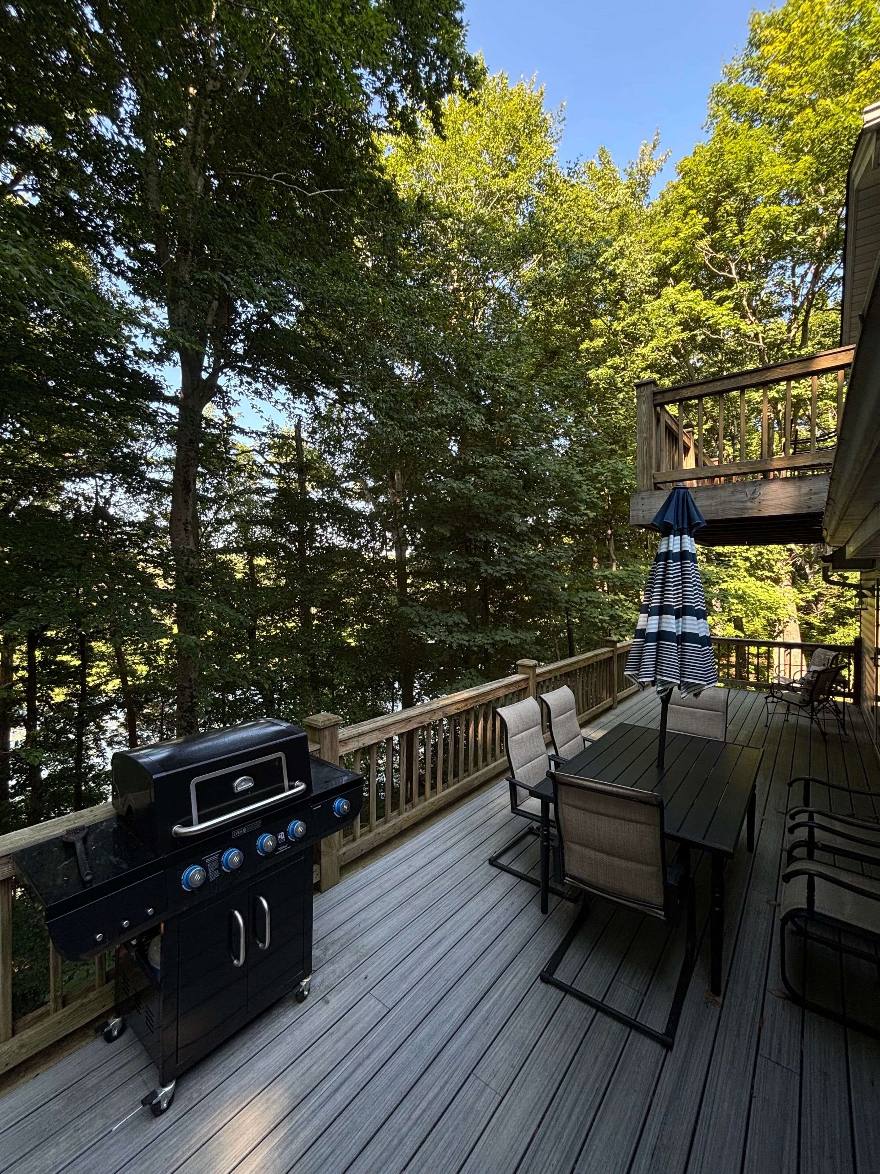 Une terrasse équipée d’un barbecue, de mobilier d’extérieur et offrant une vue sur la forêt environnante.