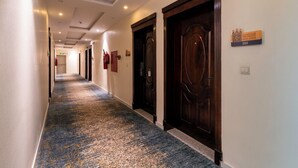Pasillo de hotel con puertas, un extintor y un letrero que indica la habitación 202.