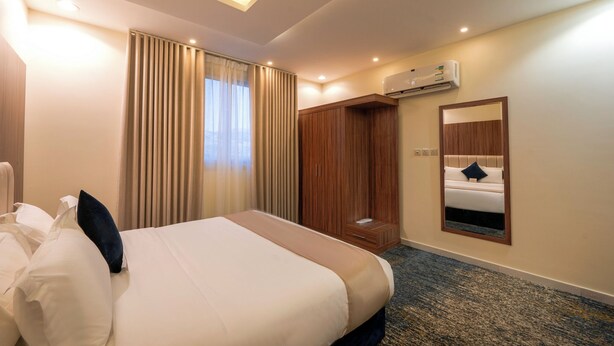 Habitación de hotel con cama, armario, espejo y aire acondicionado.