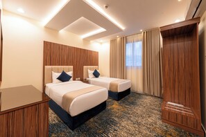 Ein Hotelzimmer mit zwei Betten, einem hölzernen Kopfteil, einem großen Spiegel und einem Teppichboden.