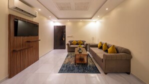 Una sala de estar moderna con un televisor de pantalla plana, un sofá, una mesa de centro y una alfombra estampada.