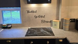 A kitchen with a countertop, a wall-mounted TV, and a motivational phrase. - 1BR Sleeps6 Elizabethline Ws98 (London)