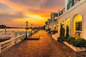 A waterfront promenade with a brick pathway, white railings, and arched windows. - Prima Amphawa (Mueang Samut Songkhram)