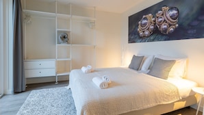 A bedroom with a bed, a white wardrobe, a white shelf unit, and a painting on the wall. - Apartment in Zeeland by Oosterschelde Beach (Sint-Annaland)