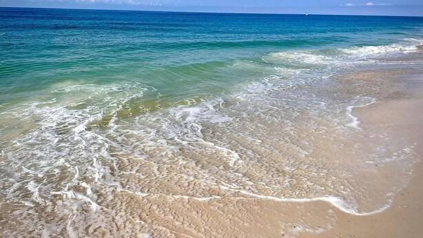 Une plage à l’eau turquoise et limpide, où les vagues sont douces.